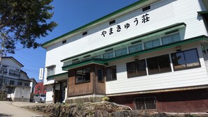 Un bâtiment avec une enseigne en caractères japonais, un mur de pierre à l’avant et un ciel bleu dégagé.