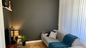 Ein gemütliches Wohnzimmer mit einem grauen Sofa, einer blauen Decke und einem Holzboden.