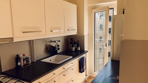 Eine moderne Küche mit schwarzer Arbeitsplatte, weißen Schränken, einer Edelstahl-Spüle und einem Gasherd.