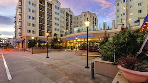 Un hotel con varios pisos, una entrada destacada y un área exterior ajardinada con jardineras y mobiliario.