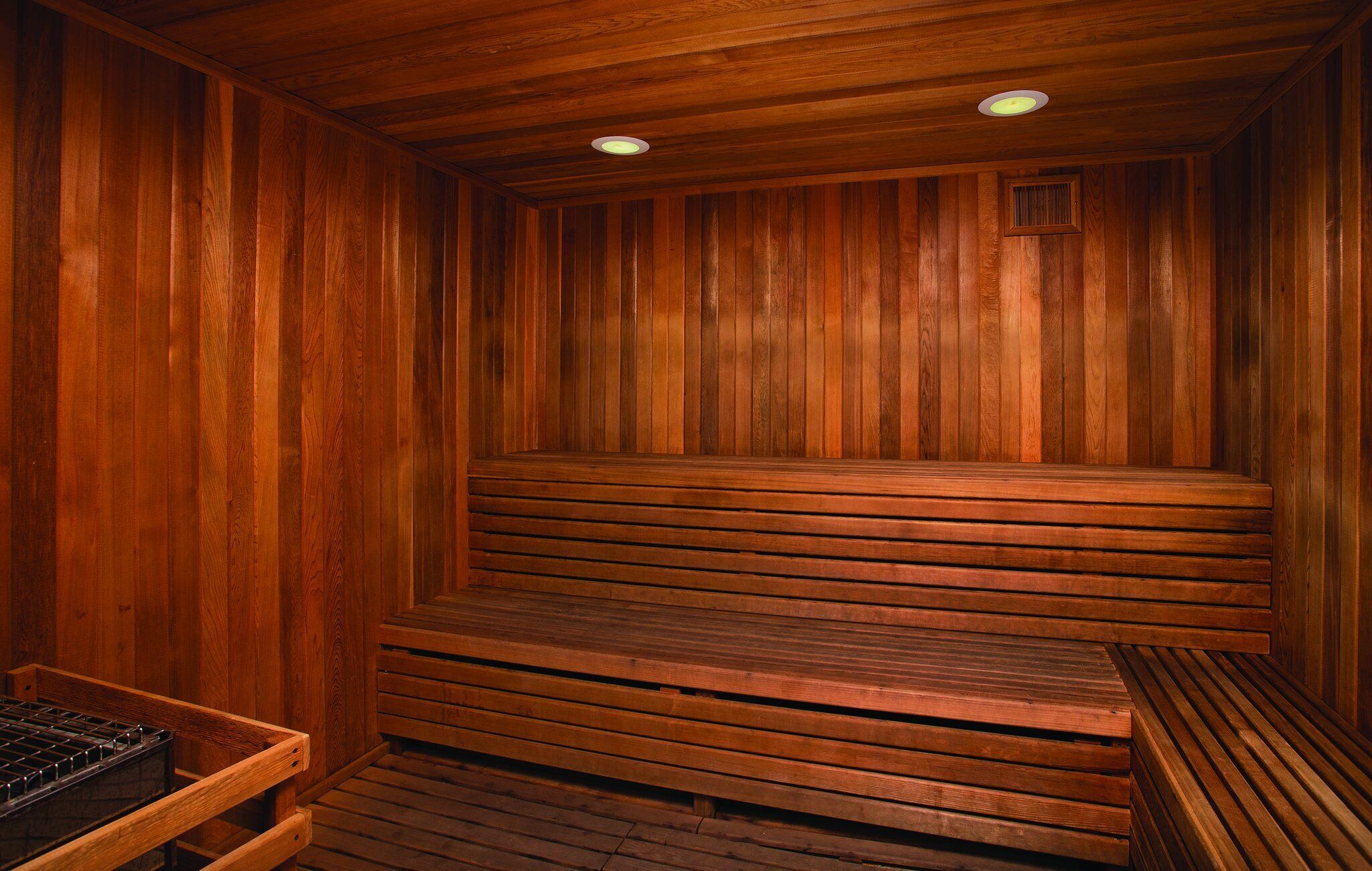 A wooden sauna with benches and a bench with a metal tray.
