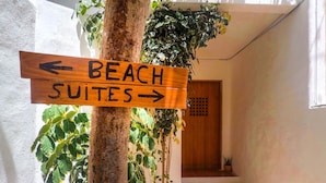 Un letrero de madera indica direcciones, señalando 'Beach Suites' y 'Playa' en sentidos opuestos.