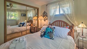 Une chambre avec un grand miroir, un lit avec de nombreux oreillers, une table de chevet avec des lampes et une fenêtre avec des rideaux.