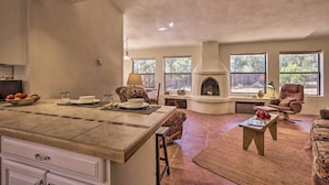 Amplia sala de estar con chimenea, ventanas grandes y una encimera de cocina.