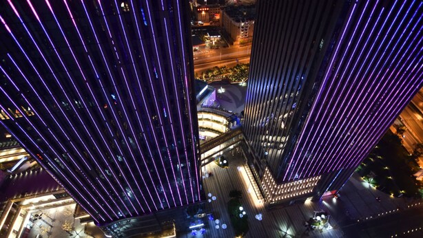 Un immeuble de grande hauteur au design moderne, caractérisé par un motif lumineux vertical bien visible sur sa façade.