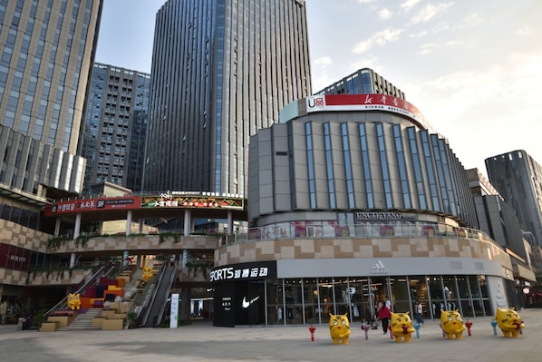 A modern urban shopping area with high-rise buildings, a curved structure with signage, and a Nike store.