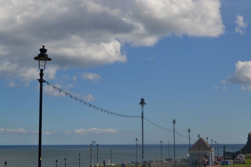 A coastal promenade with street lamps and a gazebo.