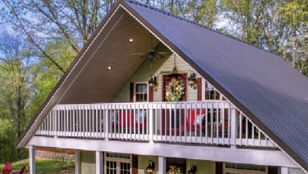 A two-story house with a balcony, a covered porch, and a gravel driveway.