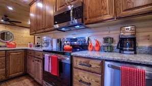 A kitchen with wooden cabinets, stainless steel appliances, and granite countertops.