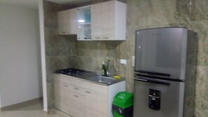 Kitchen features a gas stove, stainless steel refrigerator, and white cabinetry.