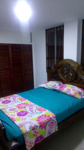 Cozy bedroom with a comfortable bed, wooden wardrobe, and a window.