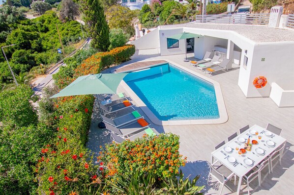 Una piscina sul tetto con poltrone a sdraio, zona pranzo e vista sul verde circostante.