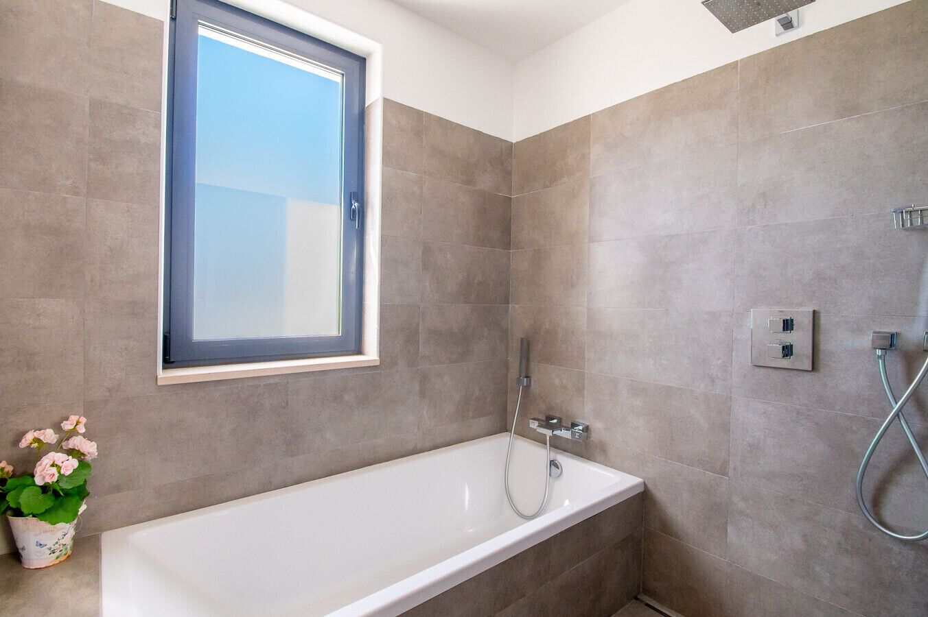 A modern bathroom with a bathtub, a shower, and a window.