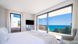 A hotel room with a large bed, a TV, a chair, and a balcony with a sea view. - Villa Centeanes Luxury villa,enviable position stunning sea views! (Carvoeiro)