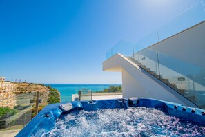 Ein modernes Gebäude mit einer Glasstiege, einem Whirlpool und Meerblick.