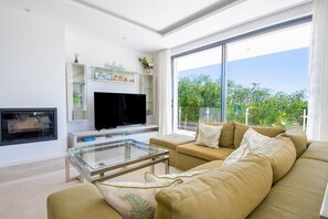 Ein modernes Wohnzimmer mit Flachbildfernseher, Glastisch und beiger Couch.