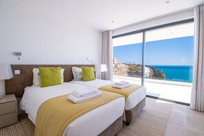 Una camera d'hotel con un letto grande, due comodini, vista mare e un balcone.
