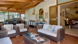 A spacious living area with wicker furniture, a glass coffee table, and a view of the outdoor patio. - Luxury villa in Sorrento Coast | Strategic location (Sant'Agata sui Due Golfi)