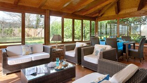 A covered patio with wicker furniture, a glass coffee table, and a dining area with a table and chairs. - Luxury villa in Sorrento Coast | Strategic location (Sant'Agata sui Due Golfi)