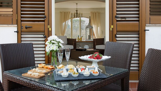 A dining table with a variety of snacks and a fruit display, surrounded by wicker chairs. - Luxury villa in Sorrento Coast | Strategic location (Sant'Agata sui Due Golfi)