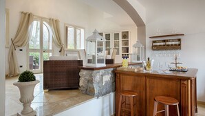 A bar area with stools, a stone accent wall, and a wine tasting sign. - Luxury villa in Sorrento Coast | Strategic location (Sant'Agata sui Due Golfi)