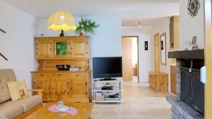 Un salon avec un téléviseur, des meubles en bois, un canapé, une table basse et une cheminée.