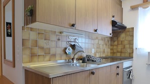 Une cuisine avec des meubles en bois, un évier en acier inoxydable et un dosseret carrelé.