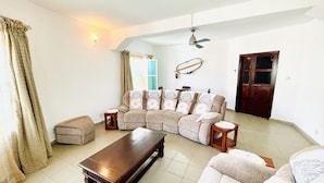 A living room with a sectional sofa, a wooden coffee table, and a ceiling fan.