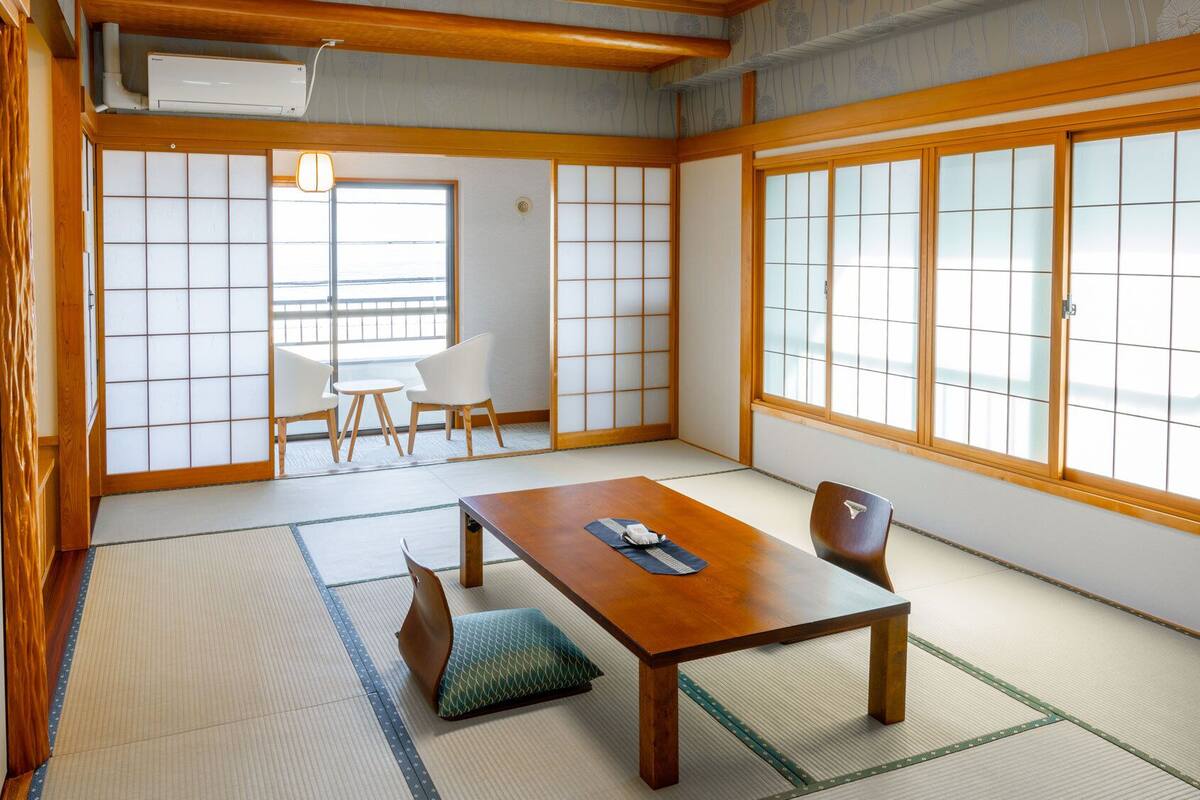A traditional Japanese room with tatami flooring, a low table, and sliding doors.