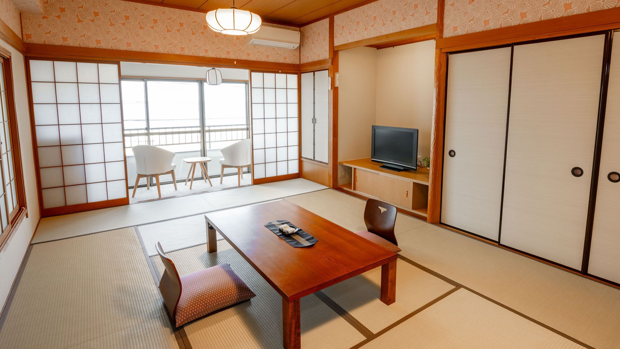 Habitació japonesa tradicional amb fusta de tatami, una taula de fusta baixa, televisió sobre una estant i portes corredisses.