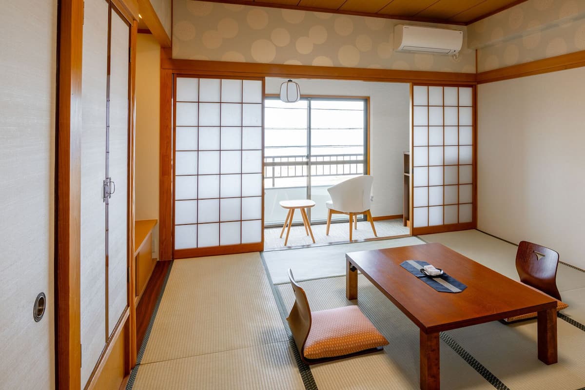 A traditional Japanese room with tatami flooring, a wooden table, and sliding doors.