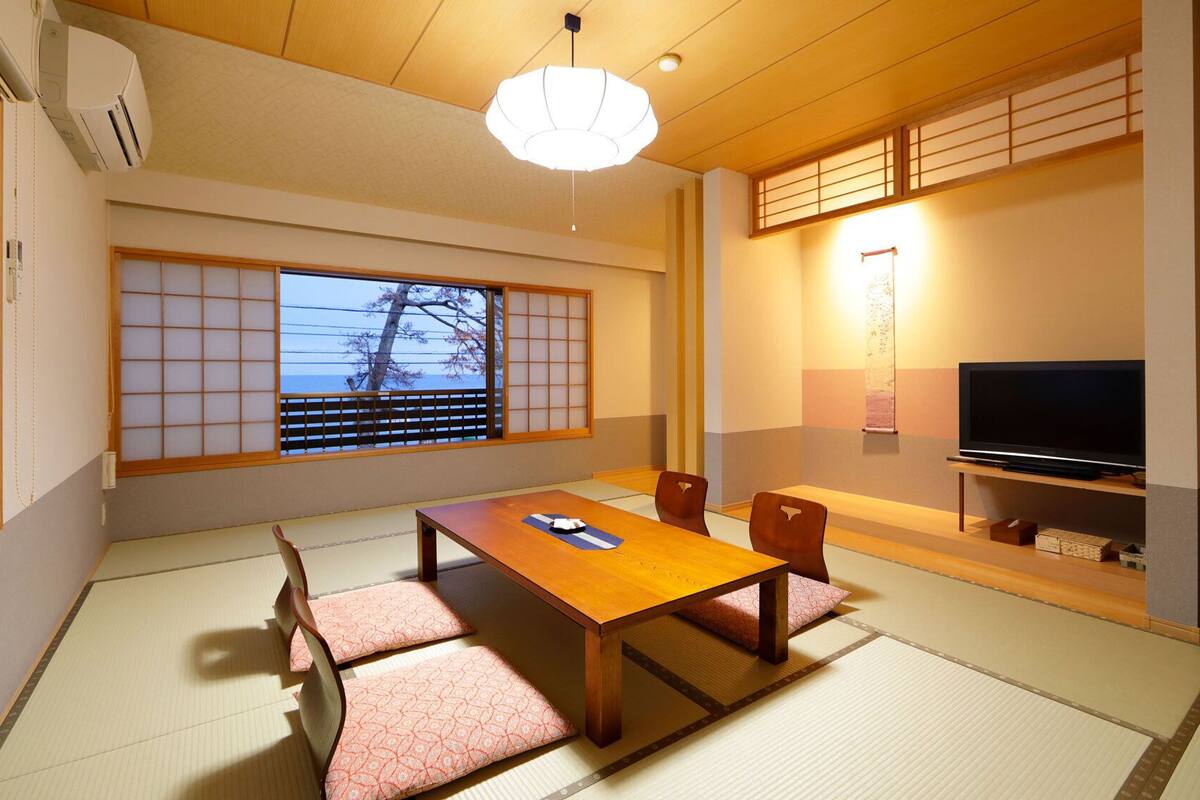 A traditional Japanese room with tatami flooring, a low table, and a television.