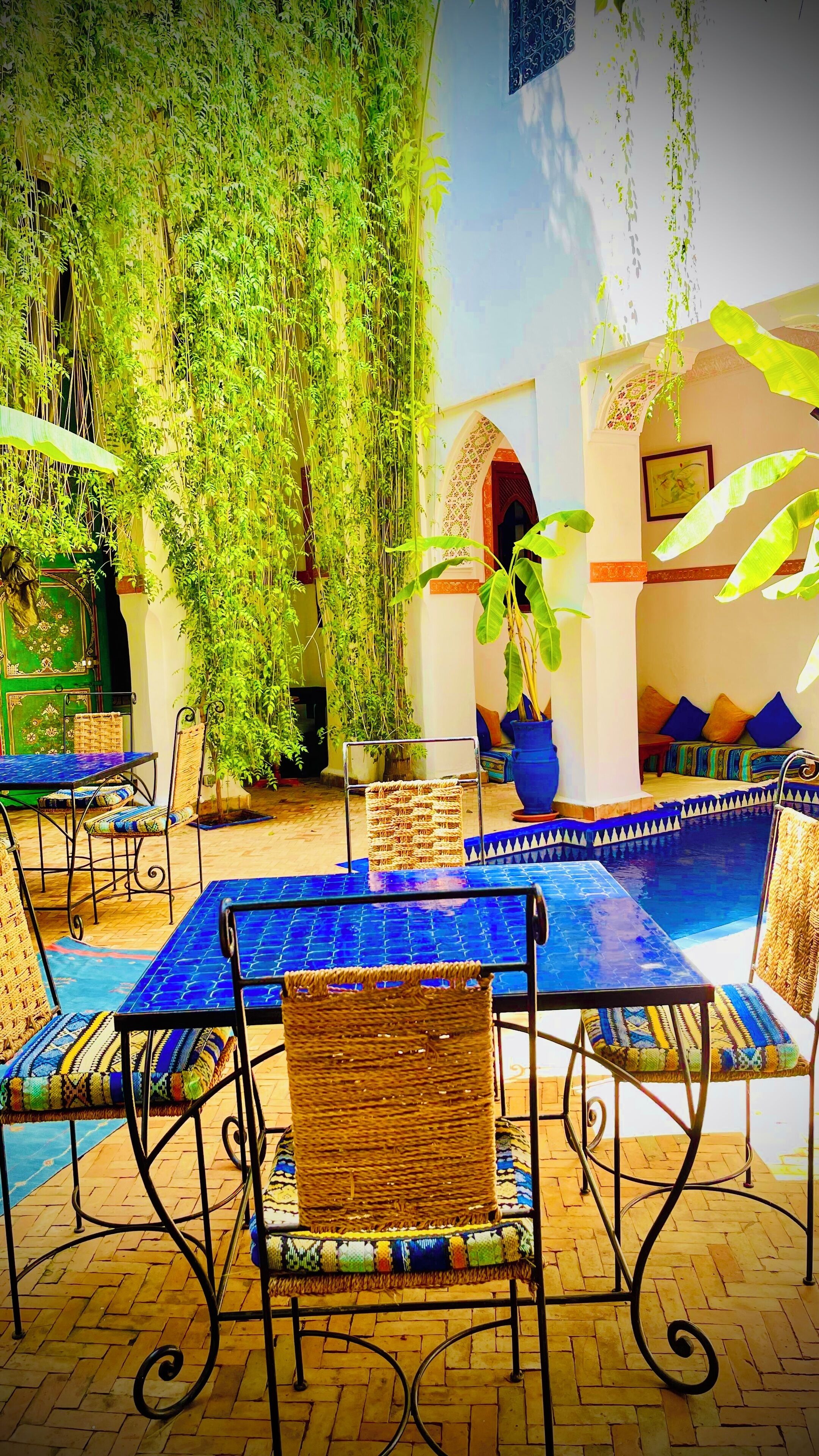 An outdoor seating area with a pool, surrounded by lush greenery and traditional decor.