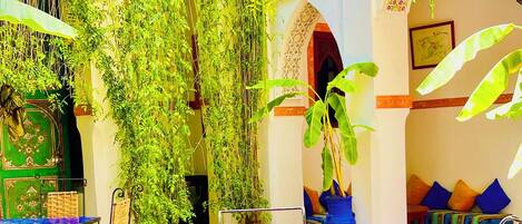 An outdoor seating area with a pool, surrounded by lush greenery and traditional decor.
