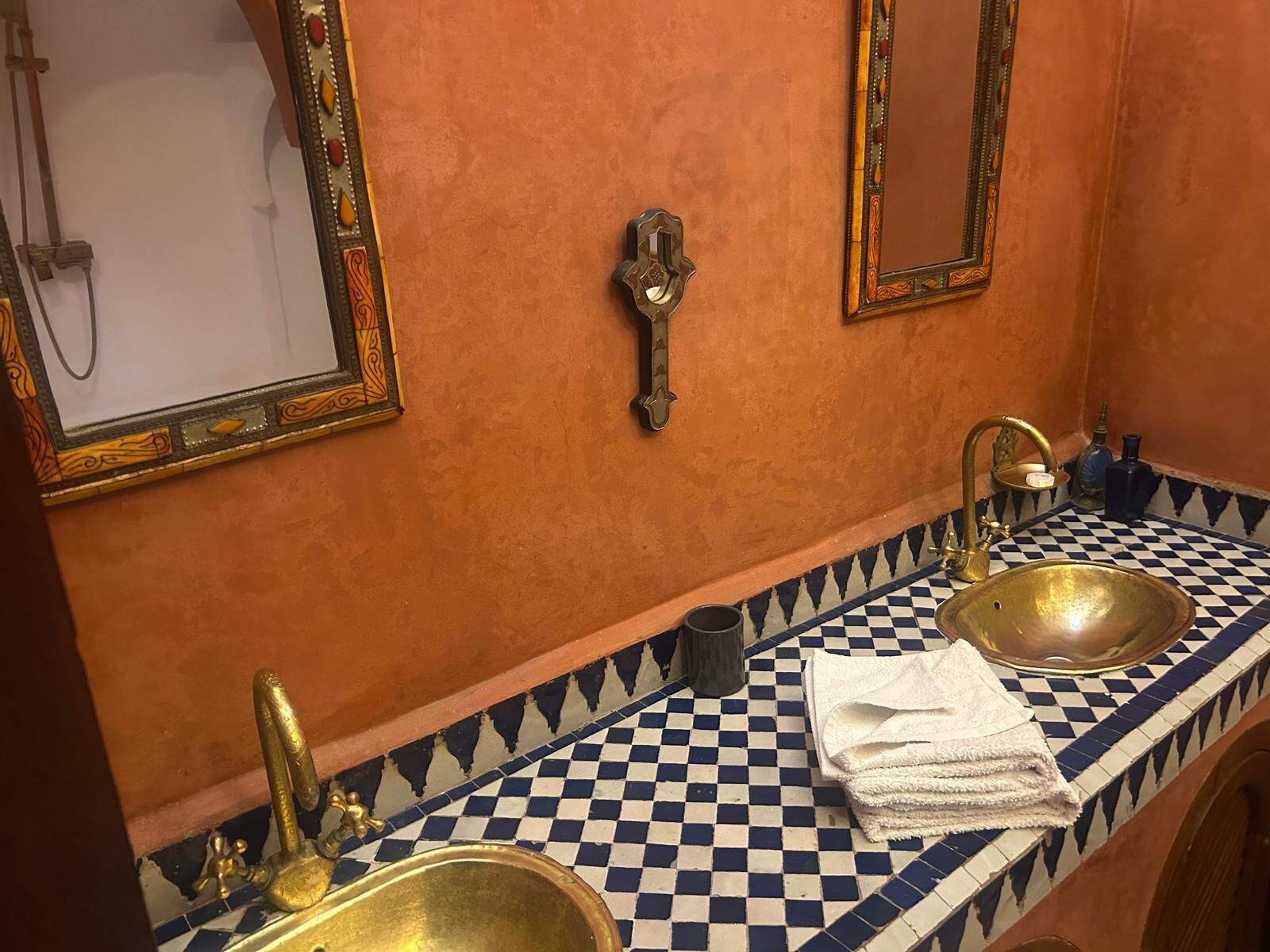 Un baño con dos lavamanos, espejos decorativos y piso a cuadros.