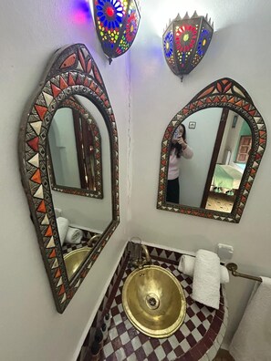 A bathroom with two ornate mirrors, a brass sink, and patterned tiles. - 19th century traditional Riad located in the heart of the medina (Marrakech)