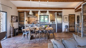 A rustic kitchen with exposed beams, a dining area with a wooden table and chairs, and a cozy seating area with cushions. - Sheepfold, 4 bedrooms, 10 people, heated pool (Bonifacio)