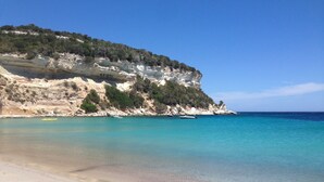 A beach with clear turquoise water, sandy shore, and rocky cliffs with sparse vegetation. - Sheepfold, 4 bedrooms, 10 people, heated pool (Bonifacio)