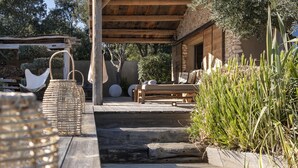A wooden deck leading to a covered outdoor seating area with a stone wall and greenery. - Sheepfold, 4 bedrooms, 10 people, heated pool (Bonifacio)