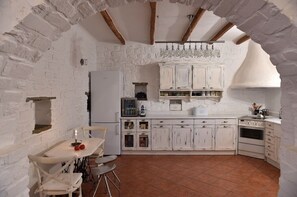 Cozy kitchen with exposed brick walls, vaulted ceiling, and oven.