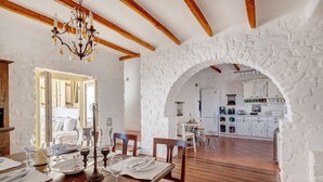 A dining area with a stone archway leading to a kitchen. - Beachfront villa with stunning sea view . (Paros)