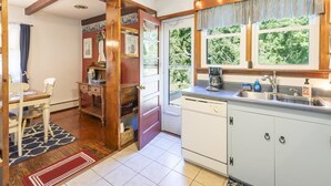 A kitchen with a dishwasher, a coffee maker, and a window with curtains. - Pet Friendly 3 Bedroom 5 Minutes to Town. (Cape May)