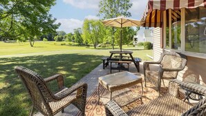 A patio with wicker furniture, a picnic table, and an umbrella. - Pet Friendly 3 Bedroom 5 Minutes to Town. (Cape May)