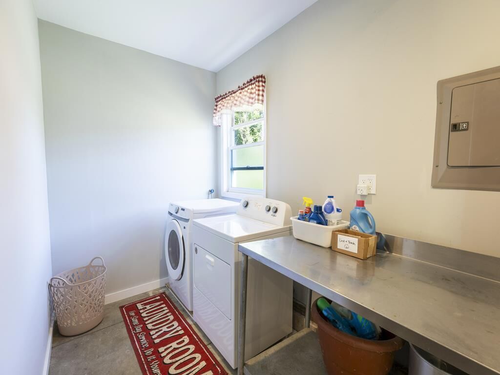 A laundry room with a washing machine, dryer, and a countertop with cleaning supplies.
