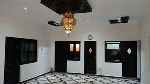 Une pièce spacieuse avec un sol à carreaux, des portes noires et un luminaire décoratif suspendu au plafond.