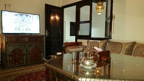 Un salon comprenant un téléviseur, un canapé, une table basse et un meuble.