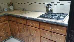 Une cuisine avec des meubles en bois, une cuisinière à gaz, une bouilloire et un évier.