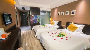 Habitación de hotel con dos camas, un escritorio con cafetera y un televisor en la pared.