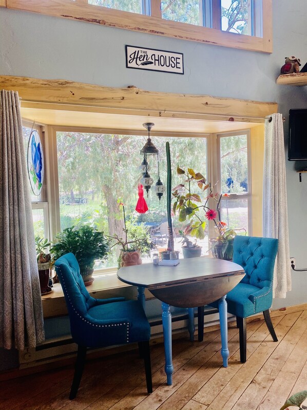Ein gemütliches Zimmer mit Holzbalkendecke, einem Tisch mit Stühlen und einem Fenster mit Vorhängen.