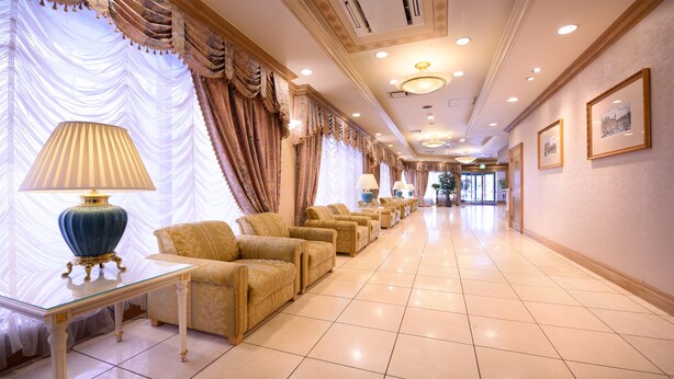 A hotel lobby with a long row of sofas, a glass table, and lamps. - Hotel Capital In Yamagata (Yamagata)
